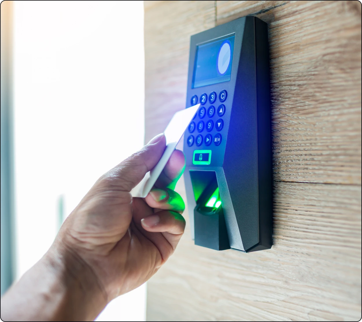 Hand using key card on security keypad.