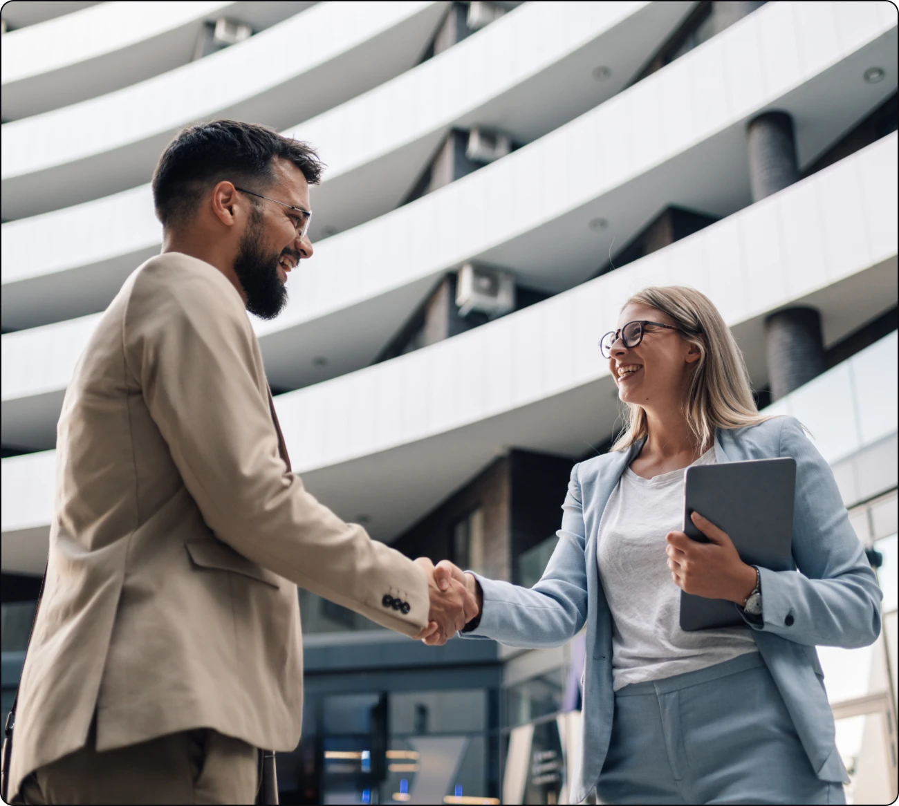 Business professionals shaking hands outside office building.